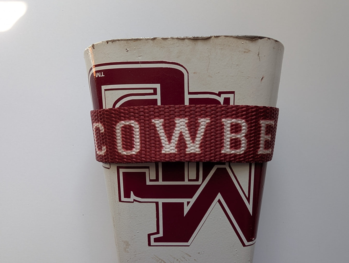 Old Cowbelt strap holstering a white cowbell